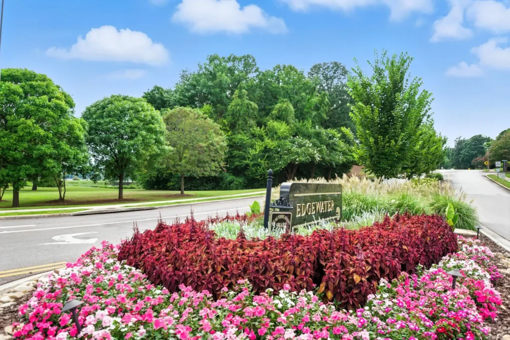 A sign that reads "Edgewater" surrounded by flowers, in the middle of two roads