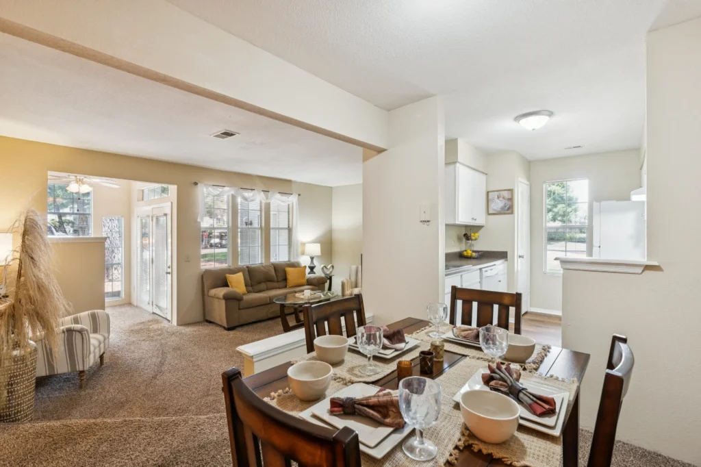A set-up dining room table in the foreground, with a living room set up in the background