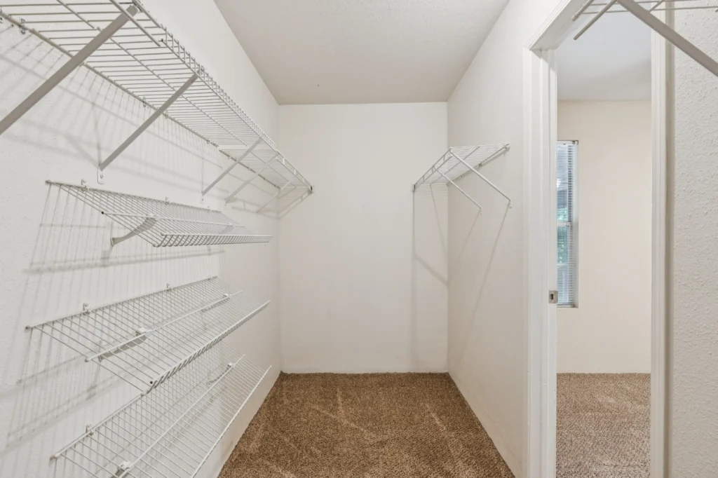 A walk-in closet with white shelving units